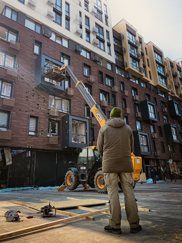 services-03 A construction worker watches as heavy machinery operates on a building facade in Kyiv, Ukraine.